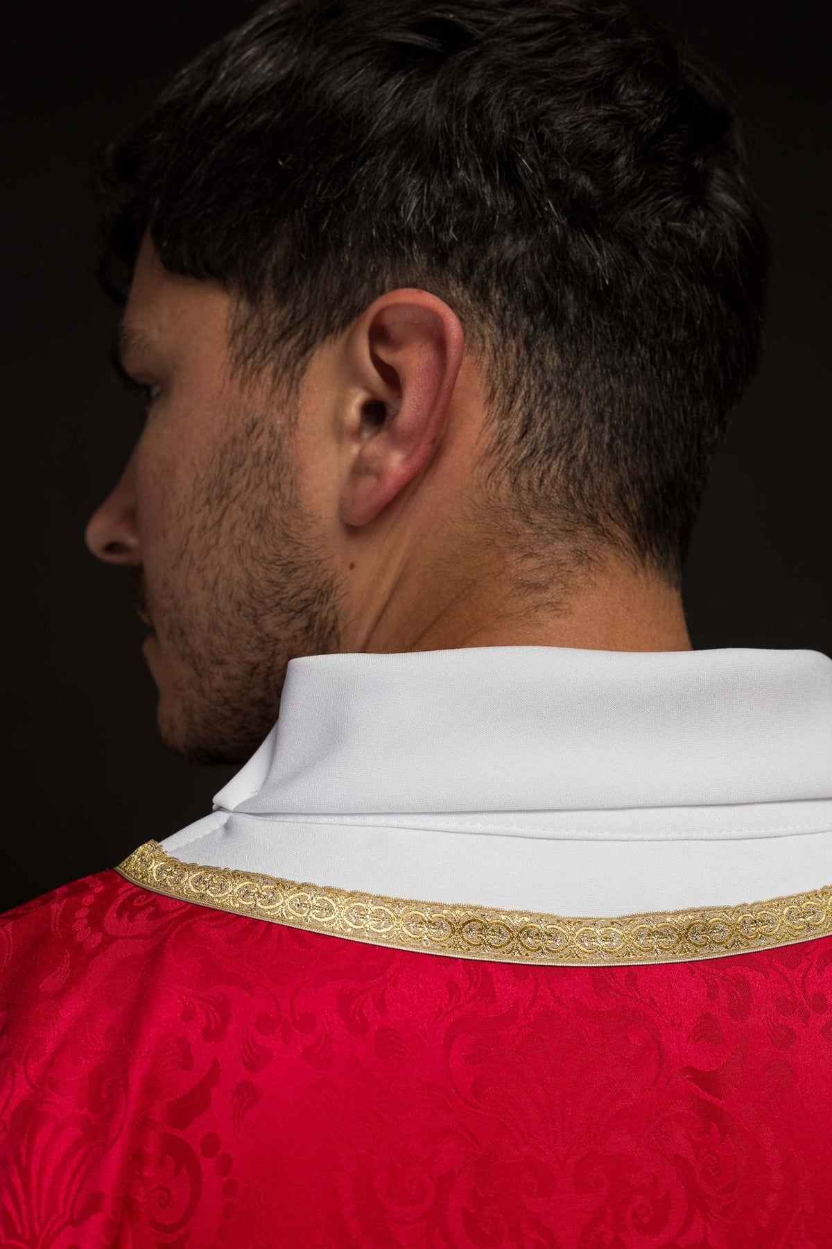 Red chasuble close-up showing white stand-up collar and gold trim