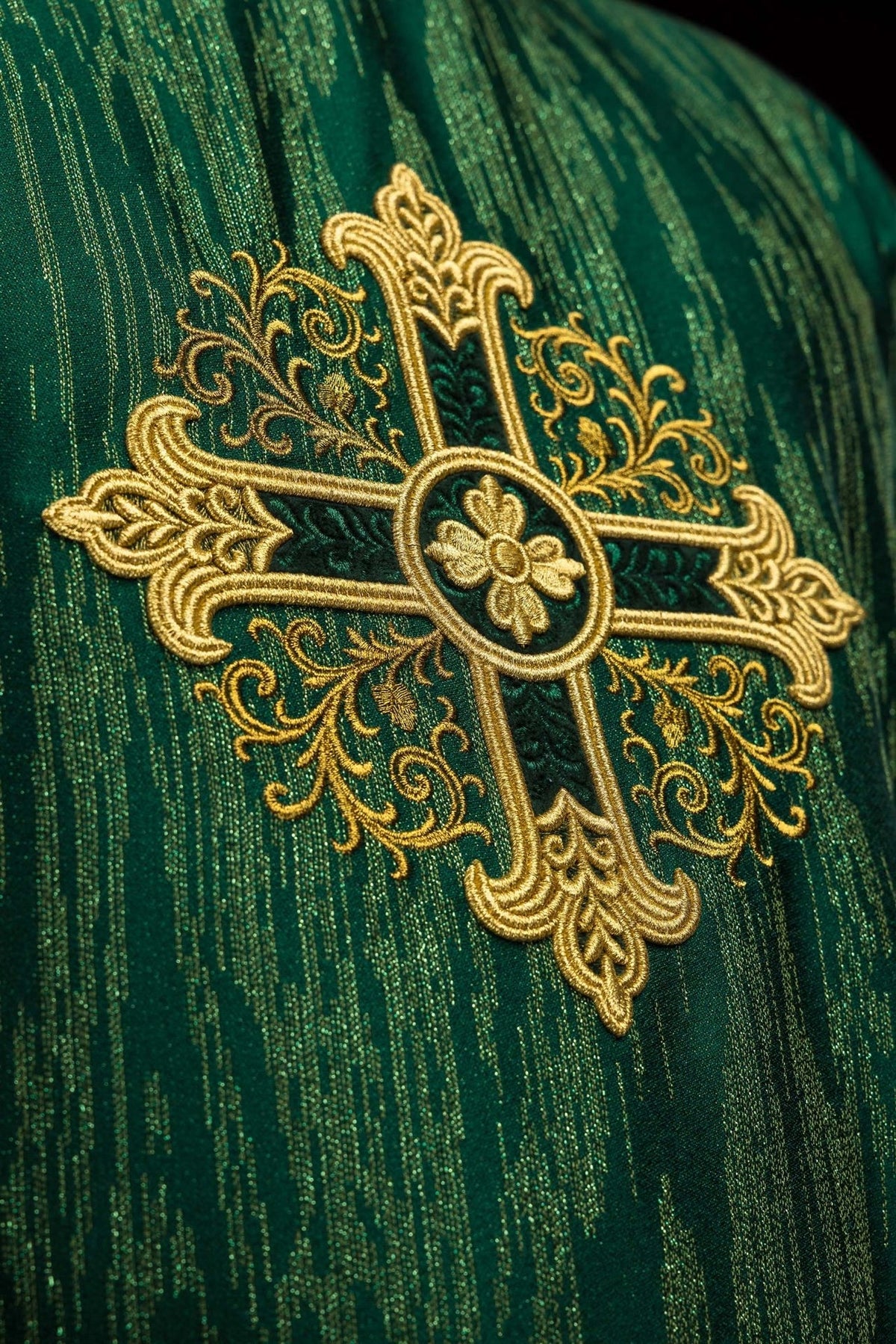 Green chasuble close-up of gold embroidered cross and decorative fabric