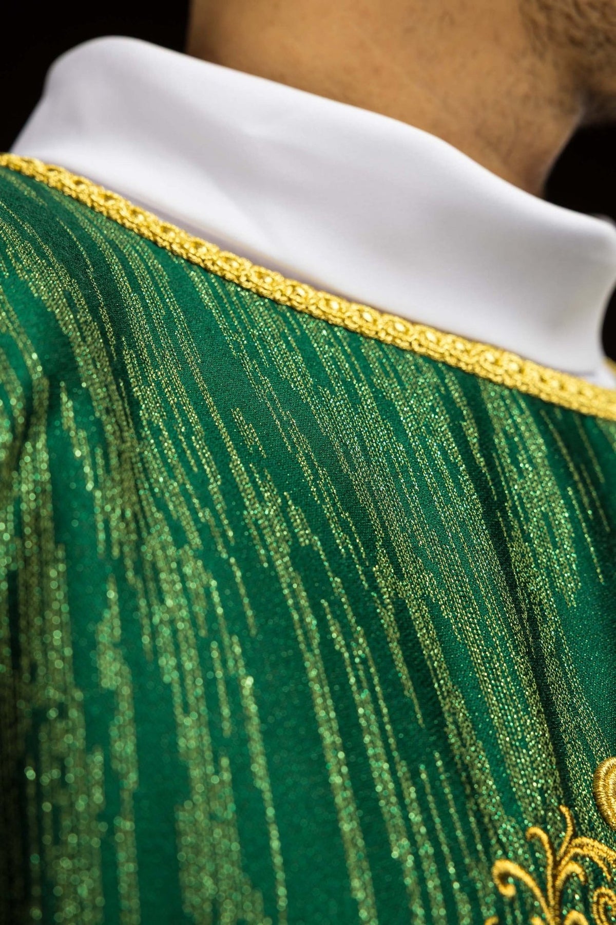Green chasuble sleeve close-up with gold trim and decorative fabric