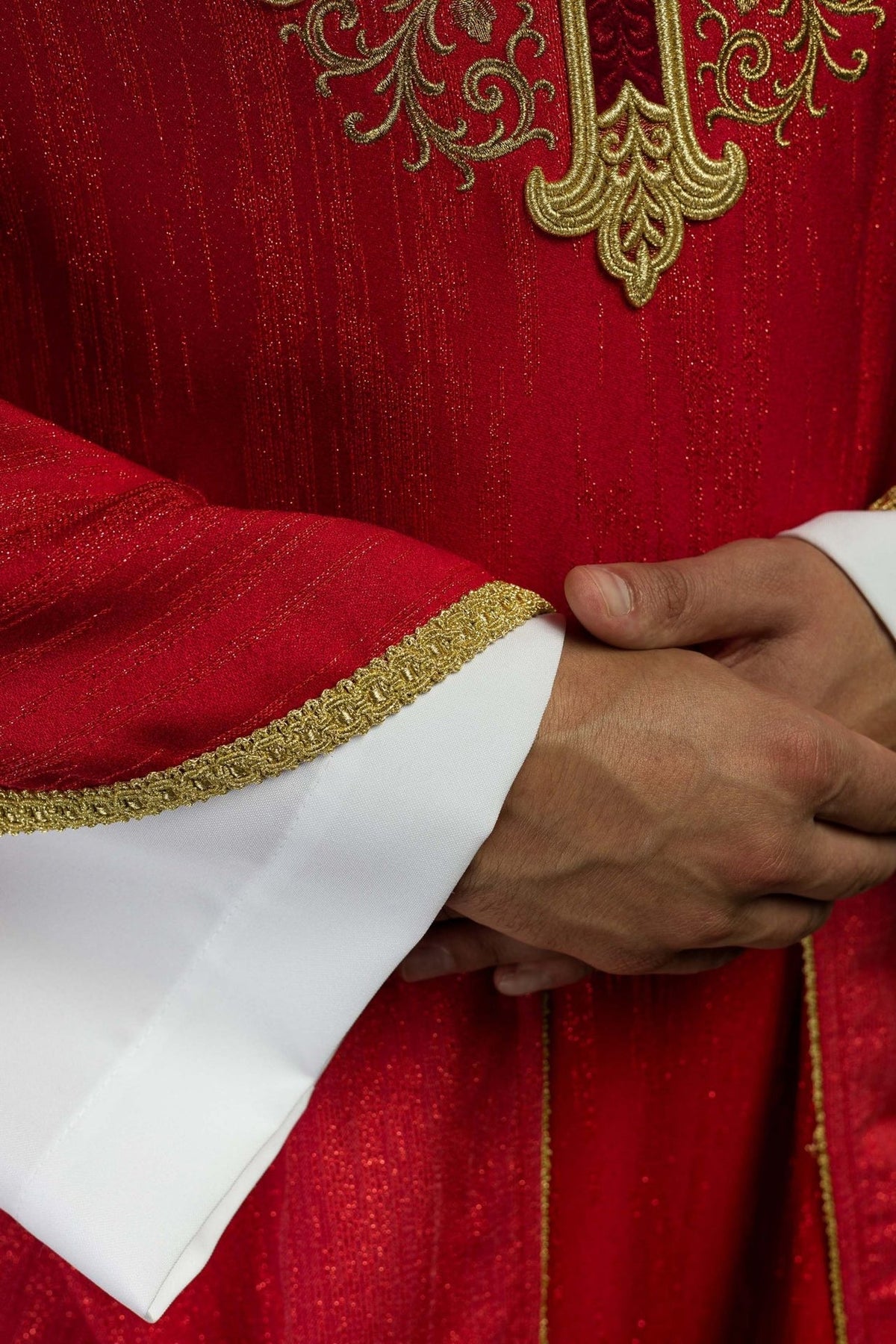 Red chasuble close-up showing gold embroidered sleeve trim