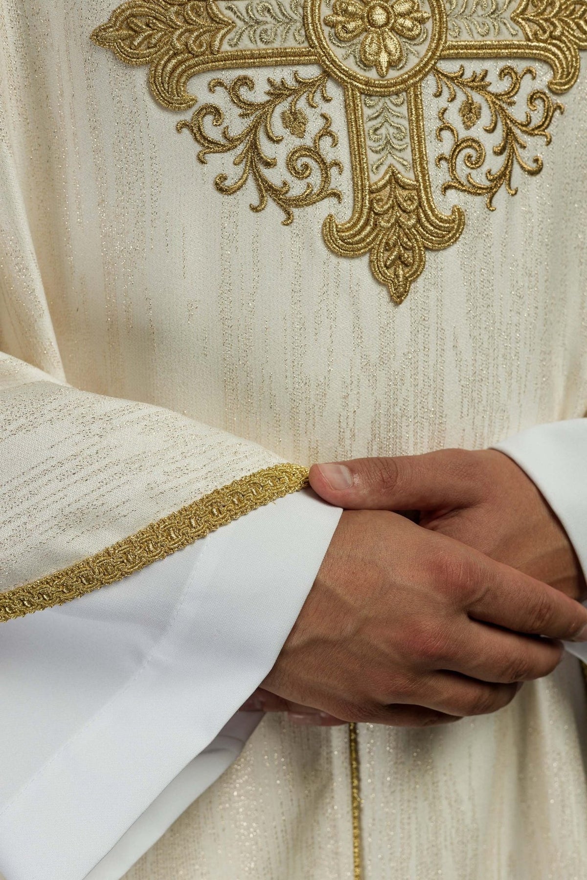 Ecru chasuble detail showing gold sleeve trim and decorative fabric