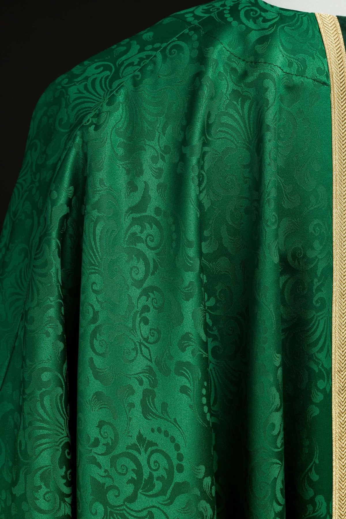 Green chasuble jacquard fabric close-up with floral motifs and gold trim