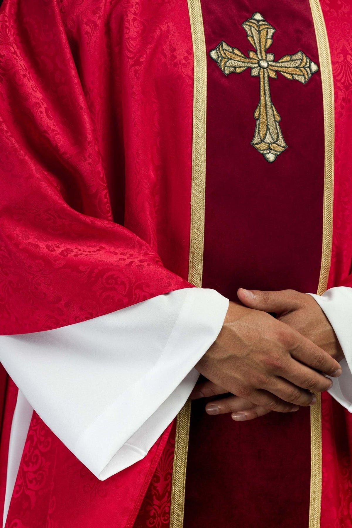 Red chasuble detail showing jacquard fabric, orphrey and white sleeve cuffs