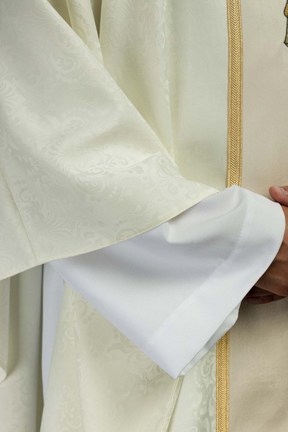 Ecru chasuble close-up showing jacquard fabric, gold trim and white lining