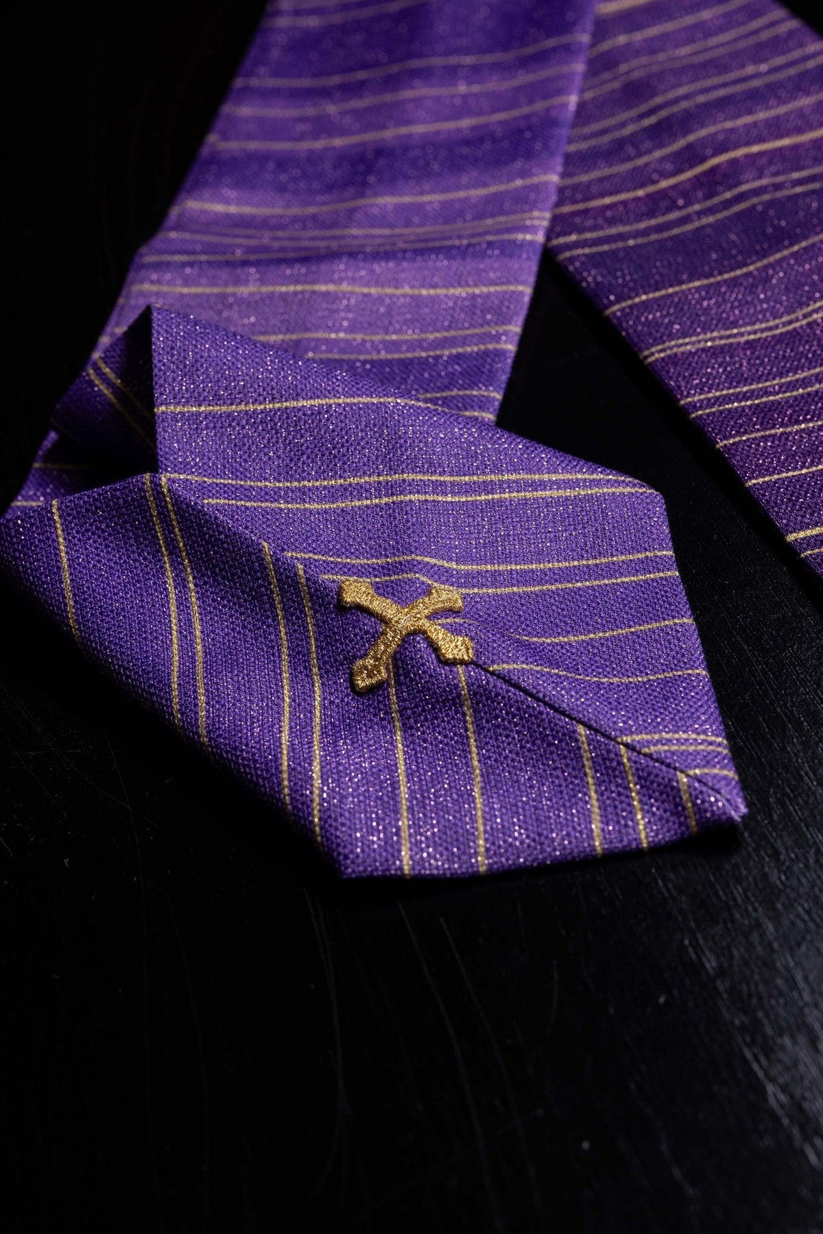 Purple Catholic chasuble close-up showing gold Jerusalem cross and striped printed fabric
