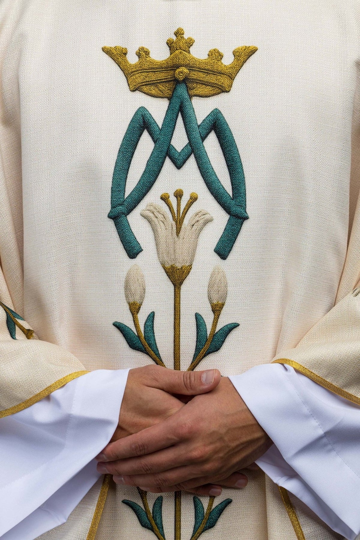 Cream chasuble close-up with blue and gold Marian monogram and lily motif