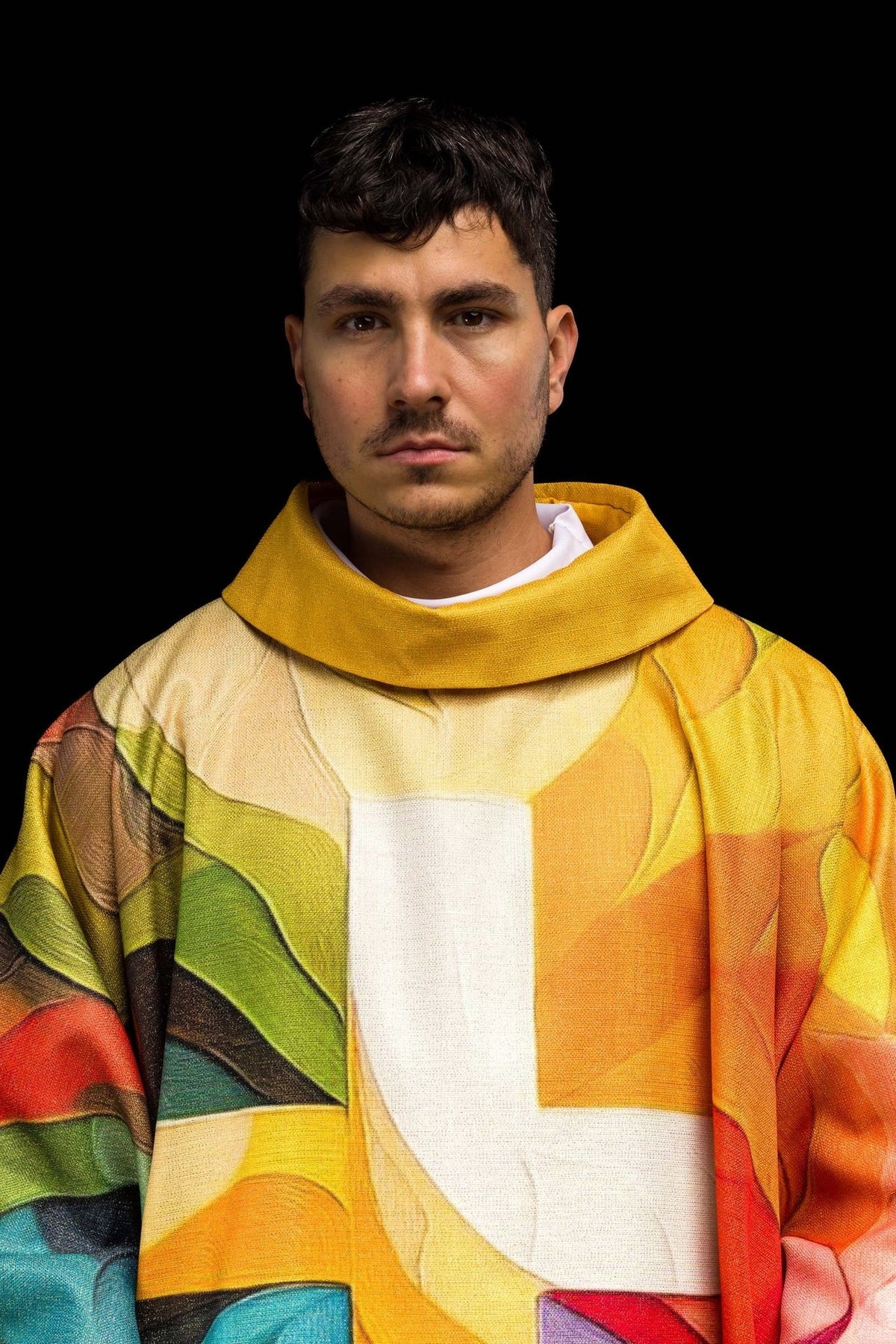 Multicolored chasuble close-up showing the gold collar and white cross motif