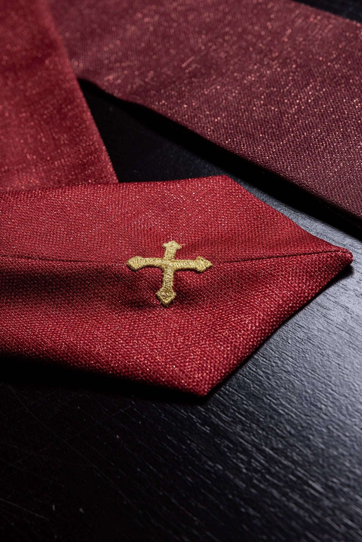 Red chasuble close-up showing gold cross embroidery on the trim