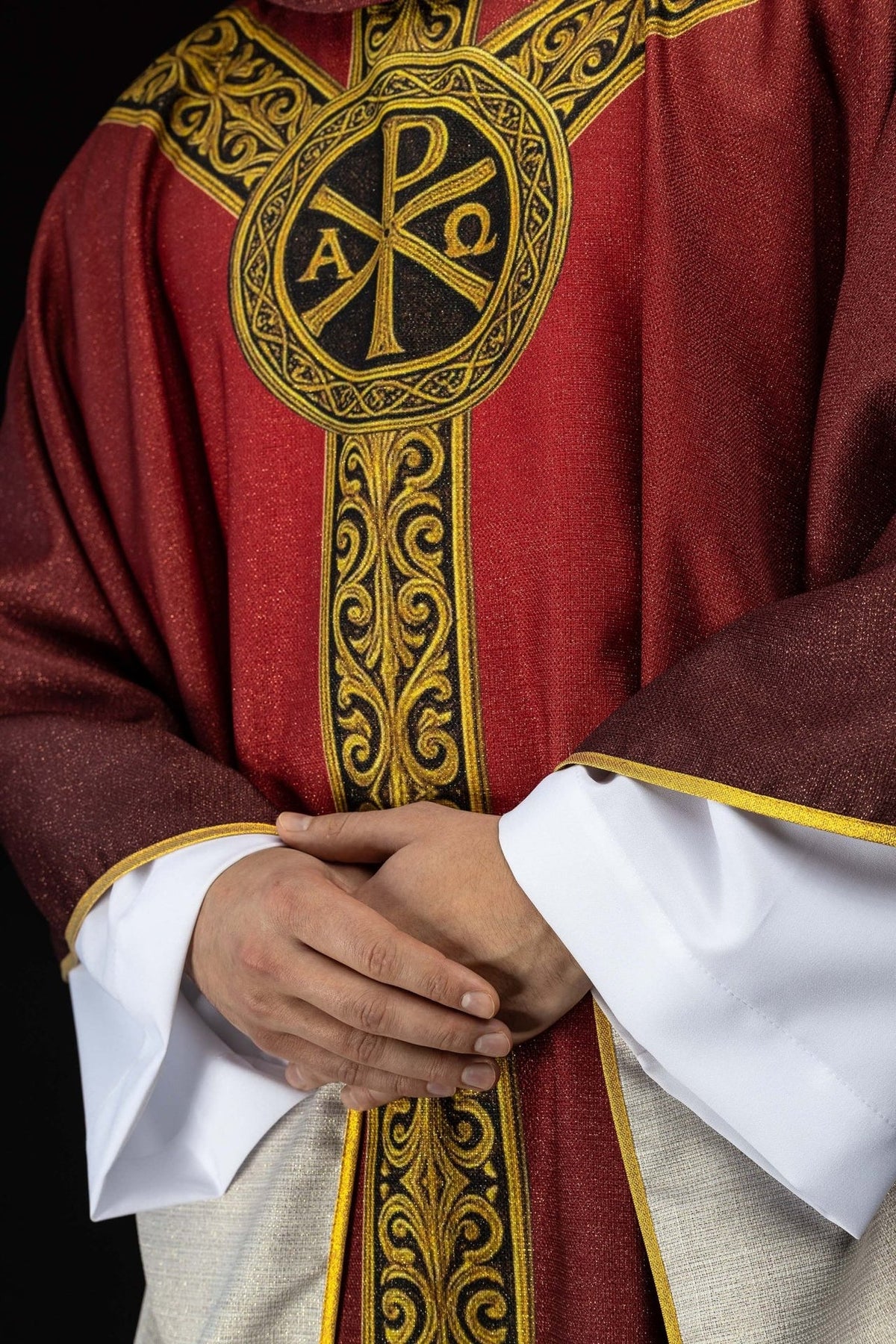Red chasuble front detail showing printed Pax symbol and gold orphrey