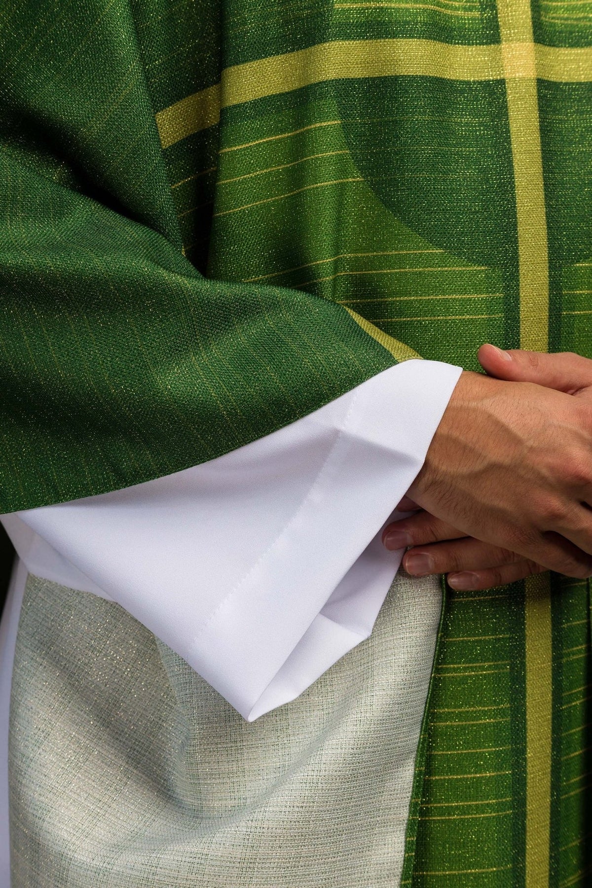 Green chasuble close-up showing cross motif and gold horizontal lines