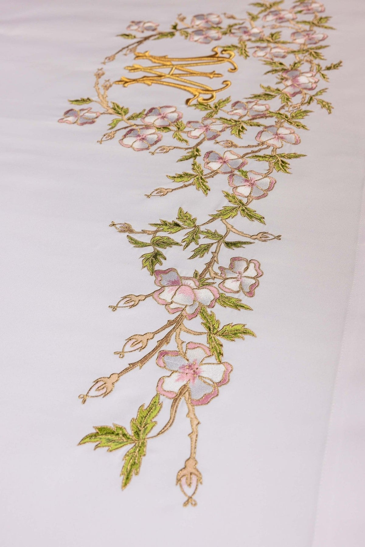 Altar cloth detail of floral embroidery and gold Marian motif on white fabric
