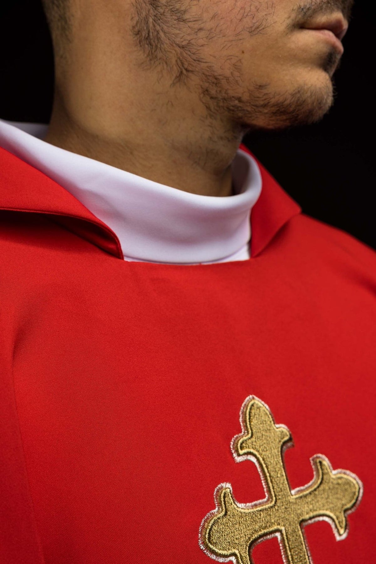Red chasuble close-up showing wide collar and partial gold cross embroidery
