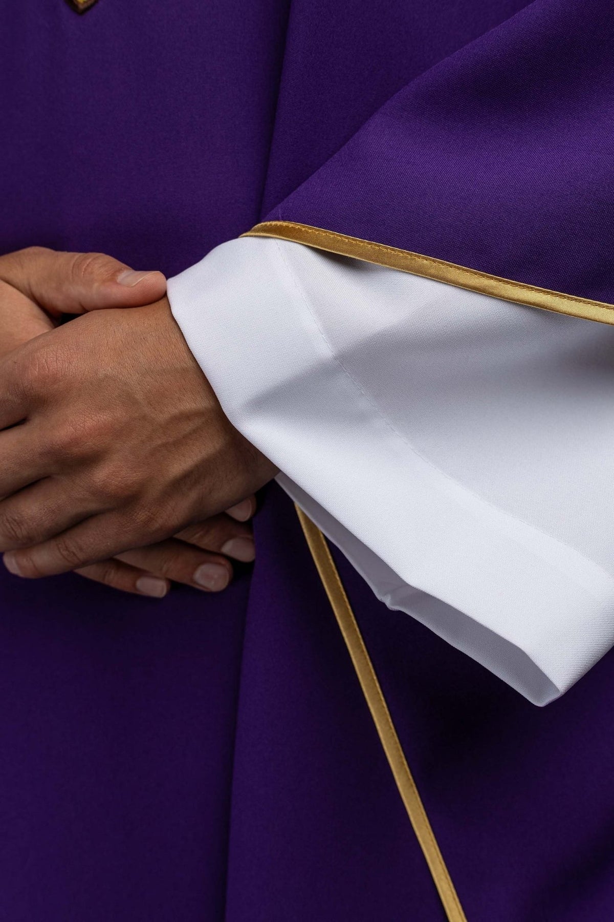 Purple chasuble detail showing white sleeve fabric and gold trim
