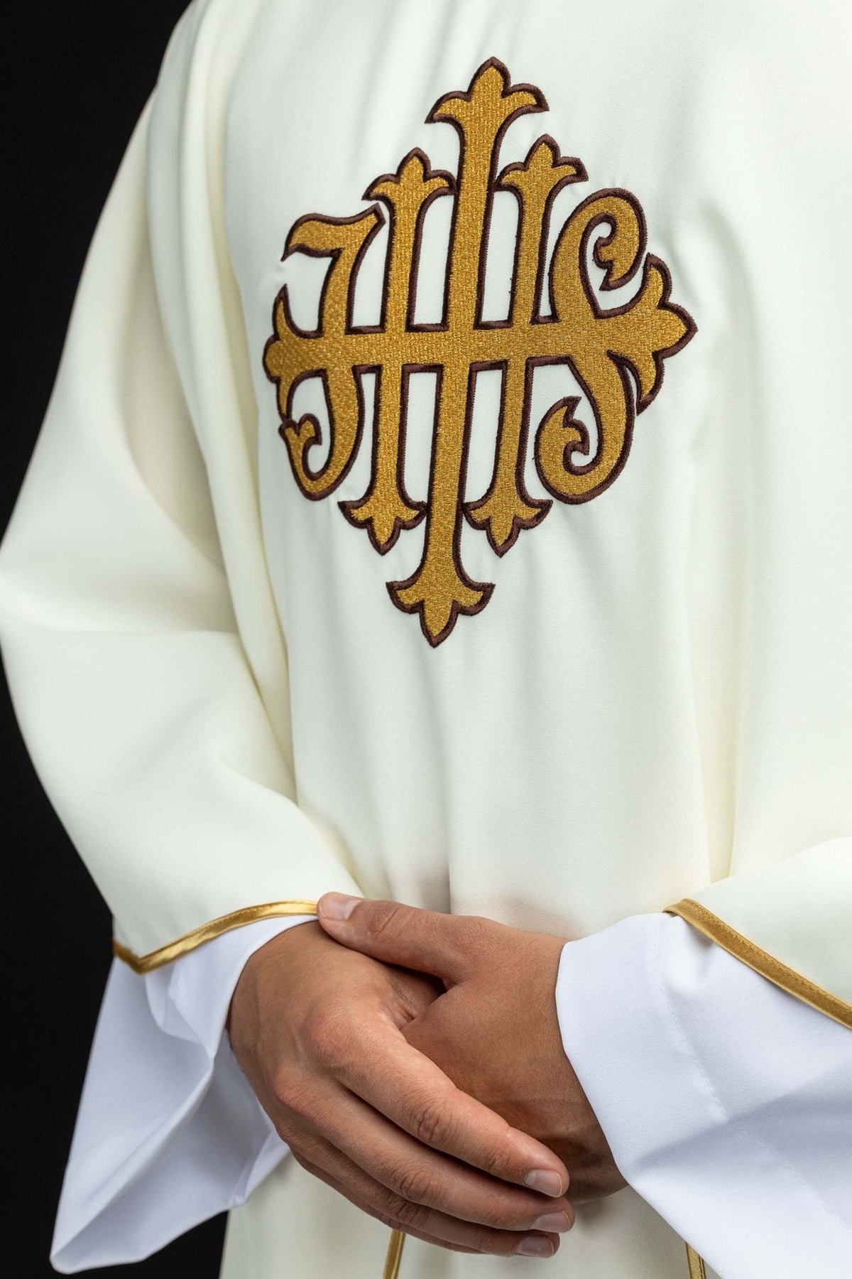 Ecru chasuble close-up showing gold JHS embroidery and gold sleeve trim