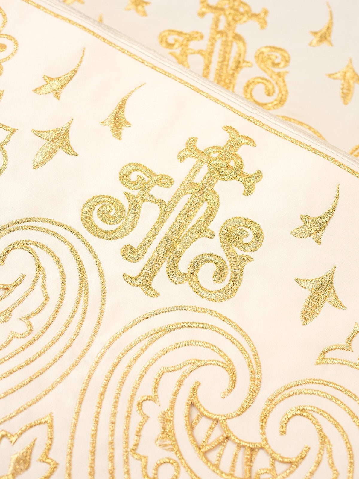 Ecru altar lace close-up showing gold IHS embroidery and decorative motifs