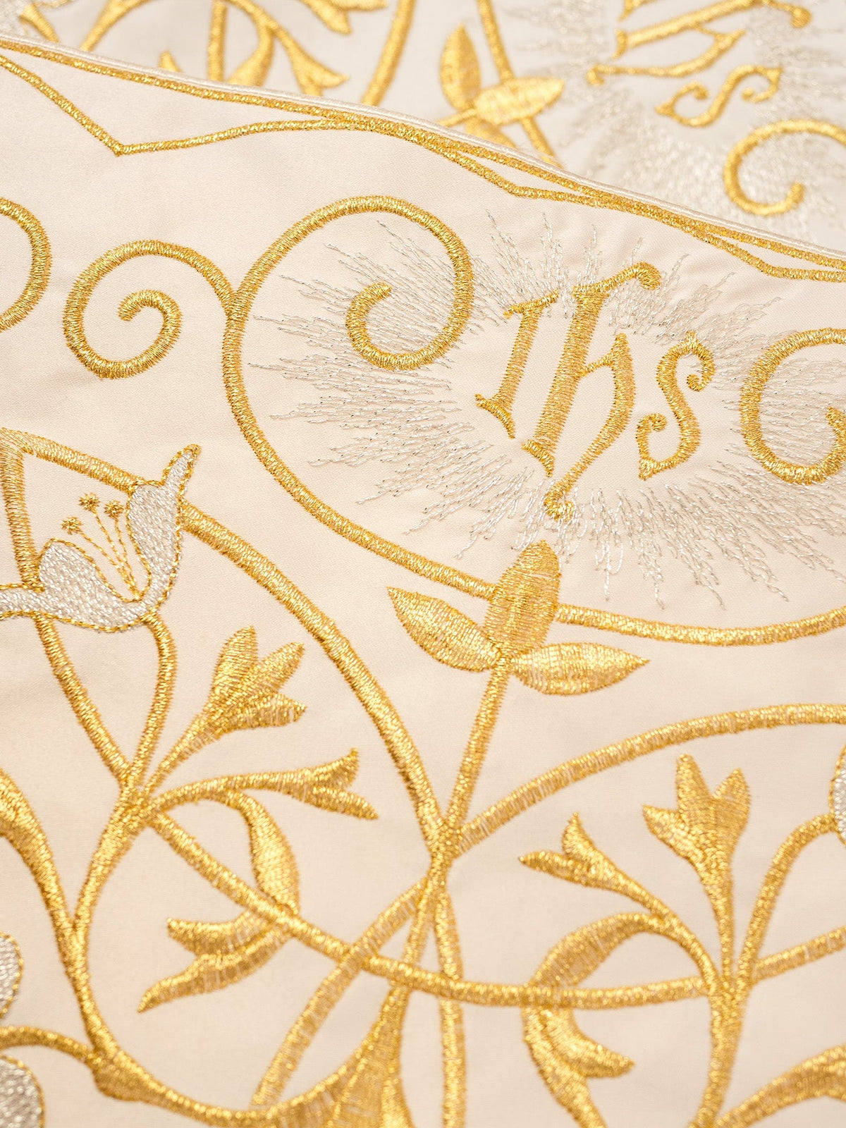 Altar lace close-up showing embroidered gold IHS monogram and floral details