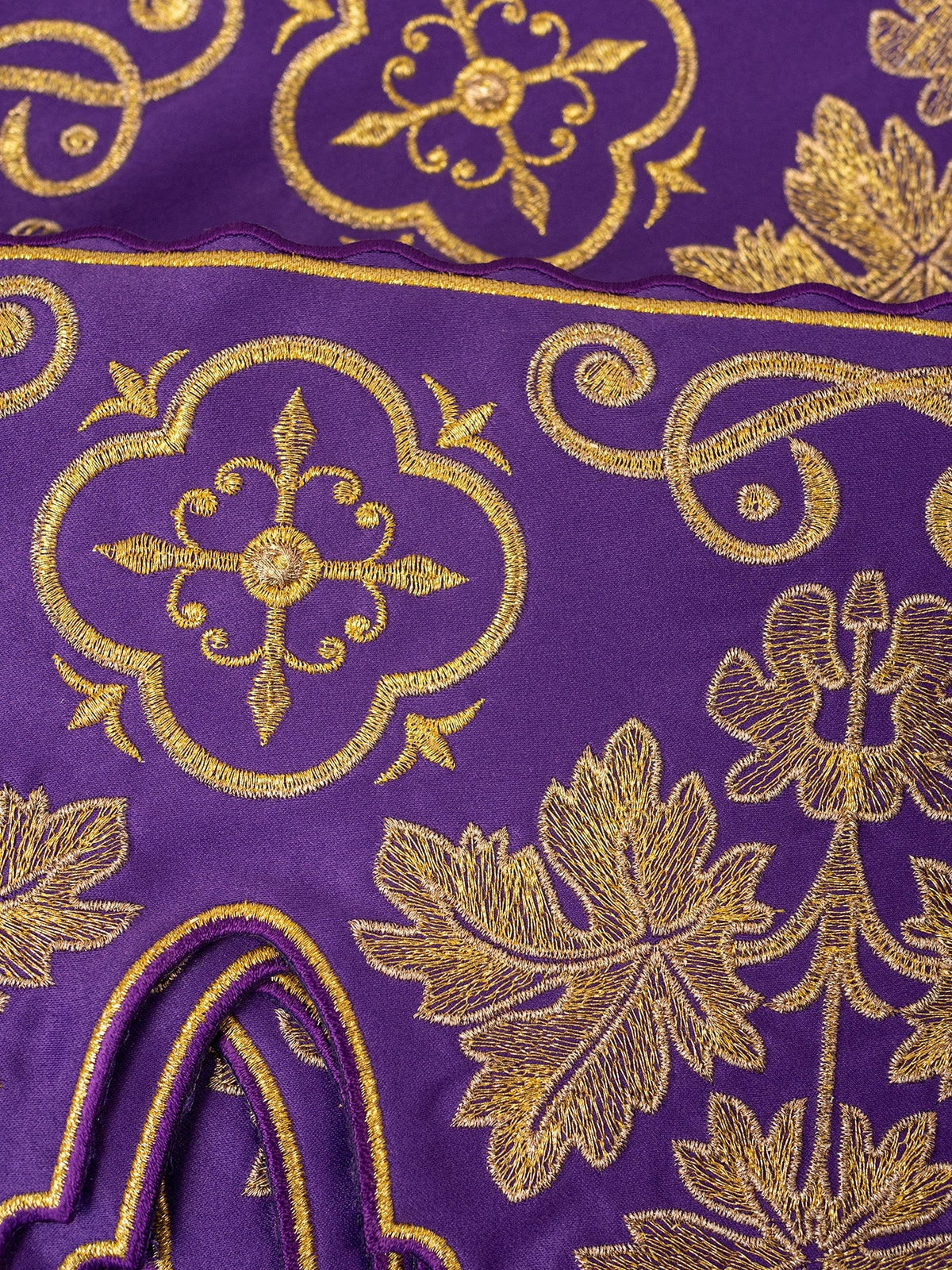 Purple altar lace close-up showing gold cross embroidery, floral motifs and finished edging