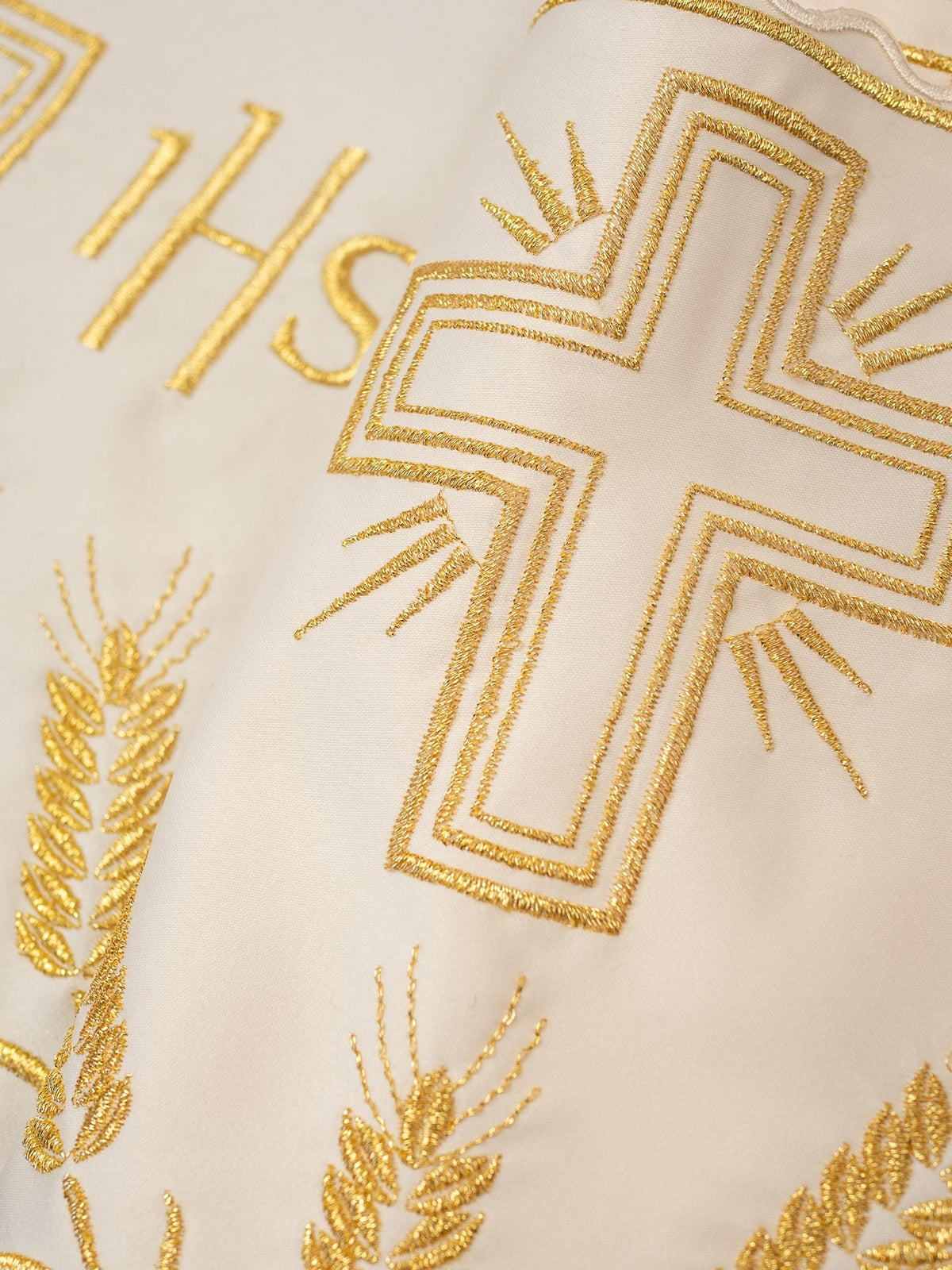 Embroidered ecru altar lace close-up with gold IHS monogram, cross and wheat motifs