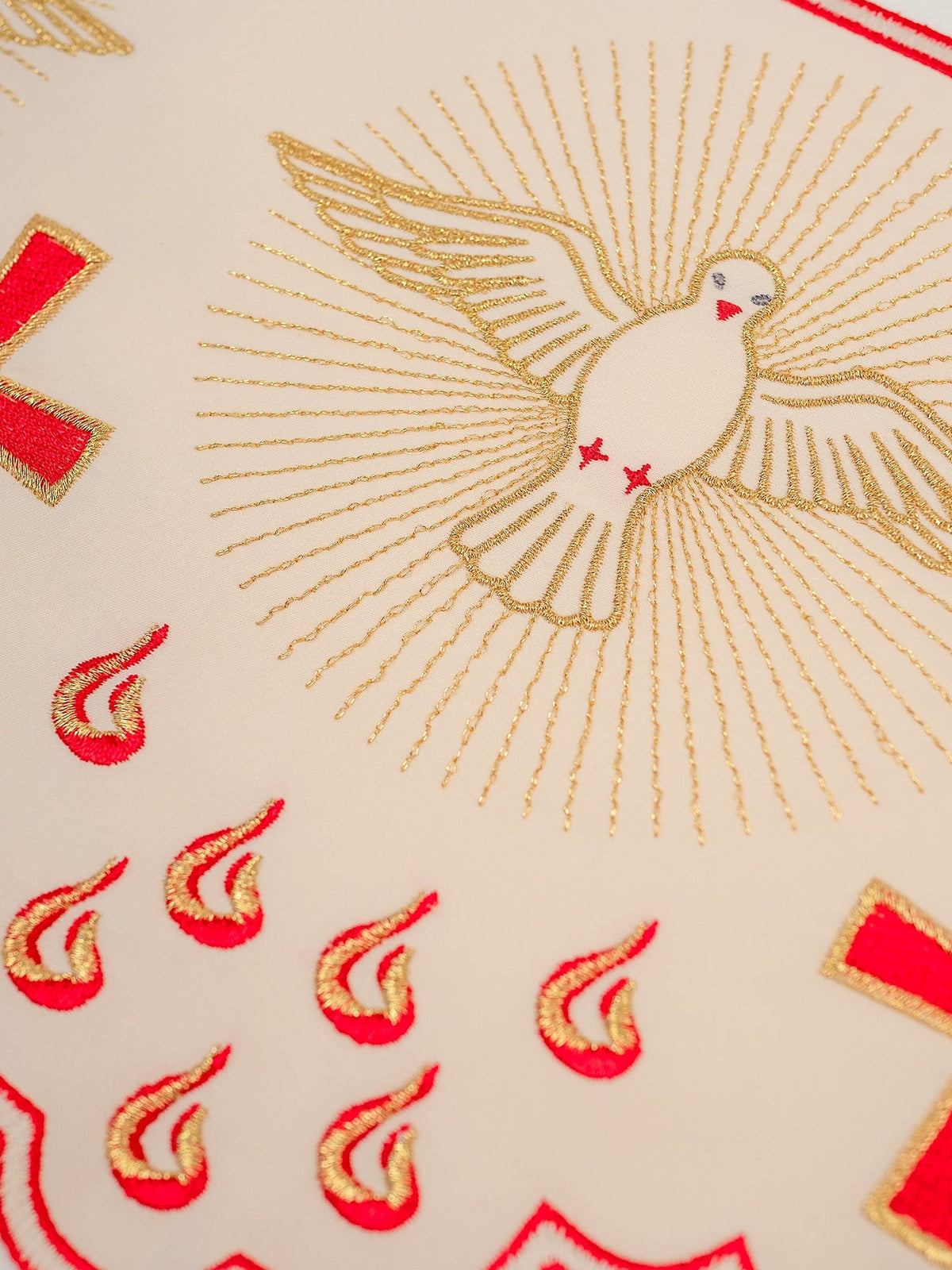 Altar lace close-up showing white dove embroidery with gold rays, red crosses and flame motifs