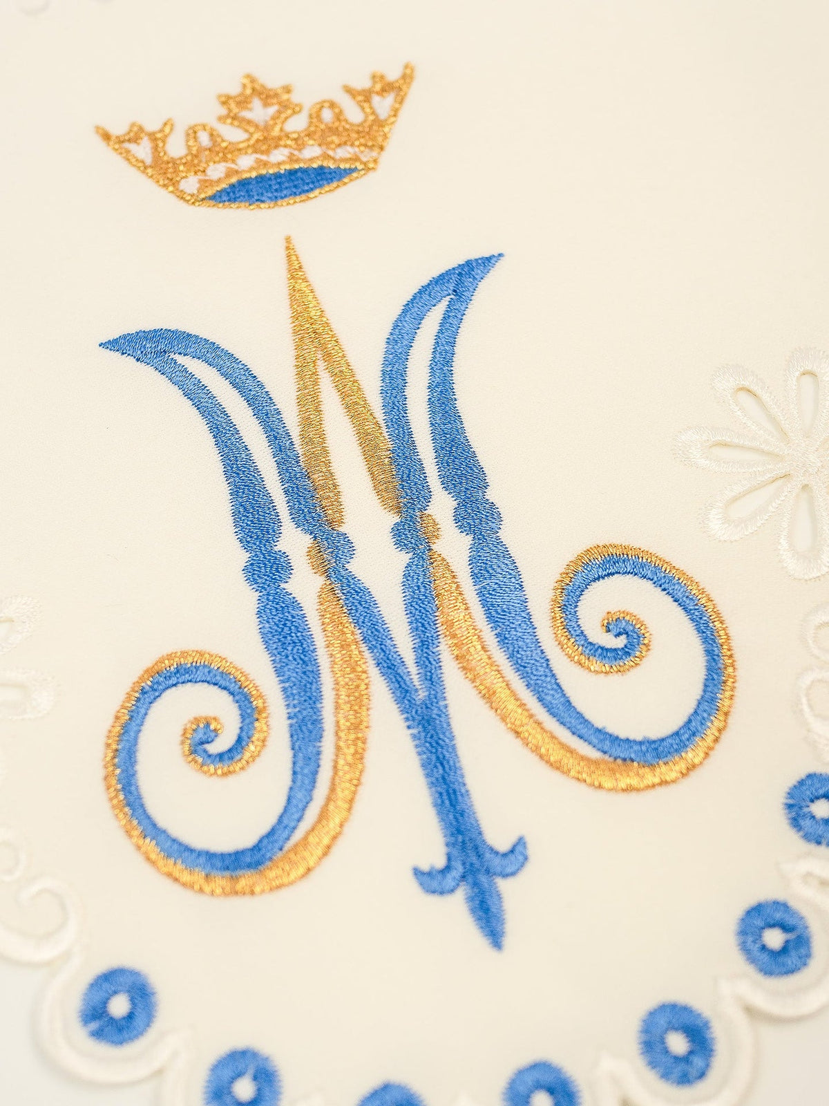 Altar lace close-up showing the Marian motif, crown and blue-and-gold embroidery