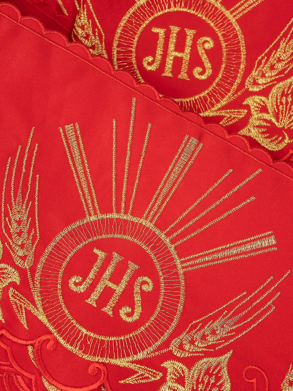 Red altar lace close-up showing gold IHS embroidery and scalloped edging