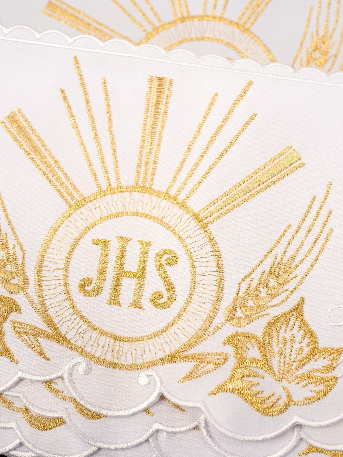 Altar lace close-up showing gold IHS embroidery, rays, floral motifs and scalloped edge