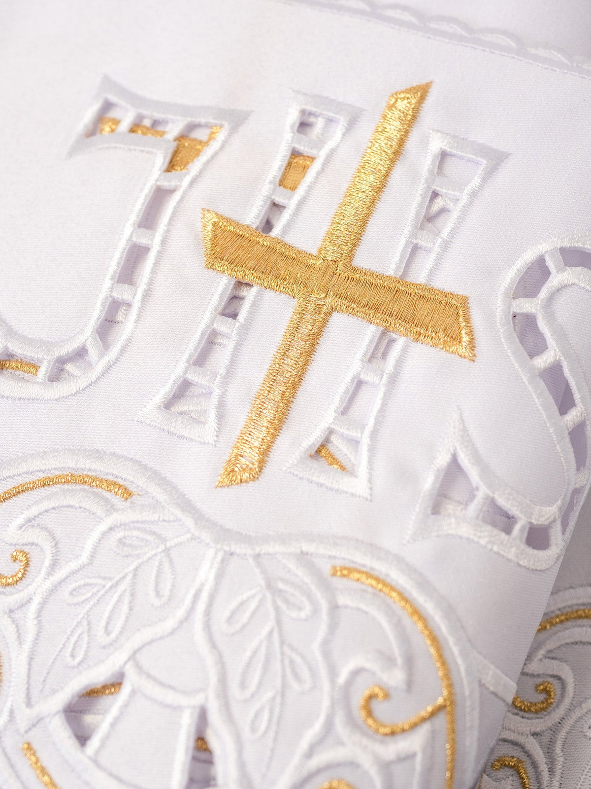 Altar lace close-up showing gold cross and white IHS embroidery