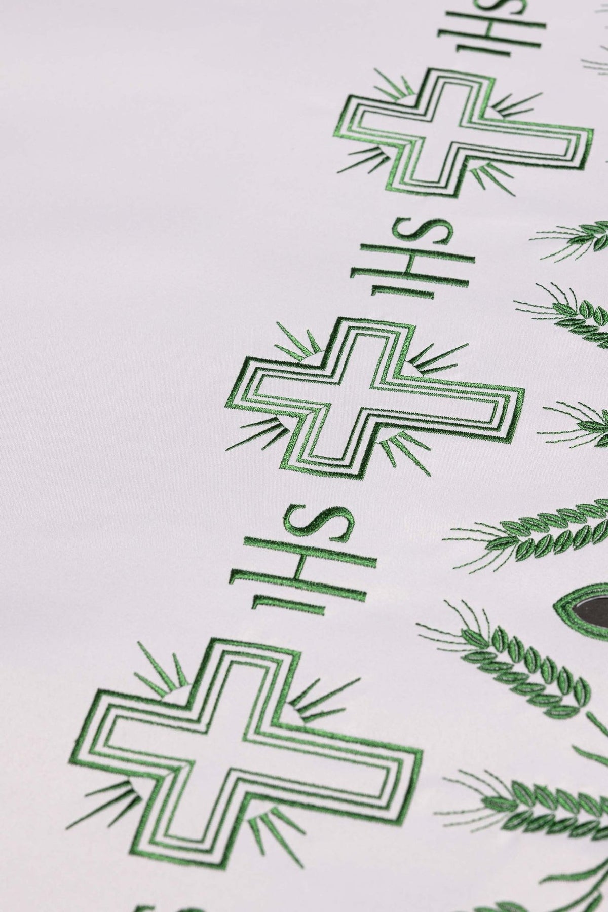 Altar cloth close-up showing repeated green cross and IHS embroidery
