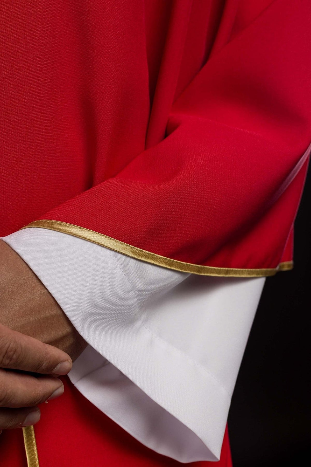 Red chasuble close-up showing gold trim along the sleeve edge