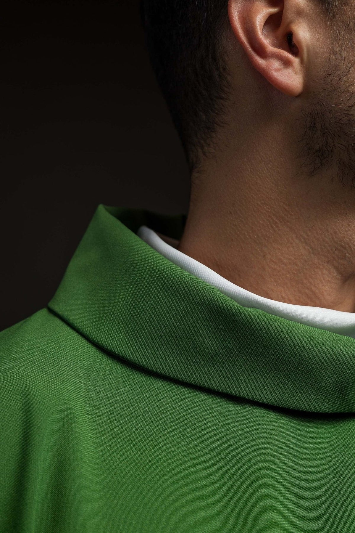 Green chasuble side detail with gold trim and flowing satin fabric