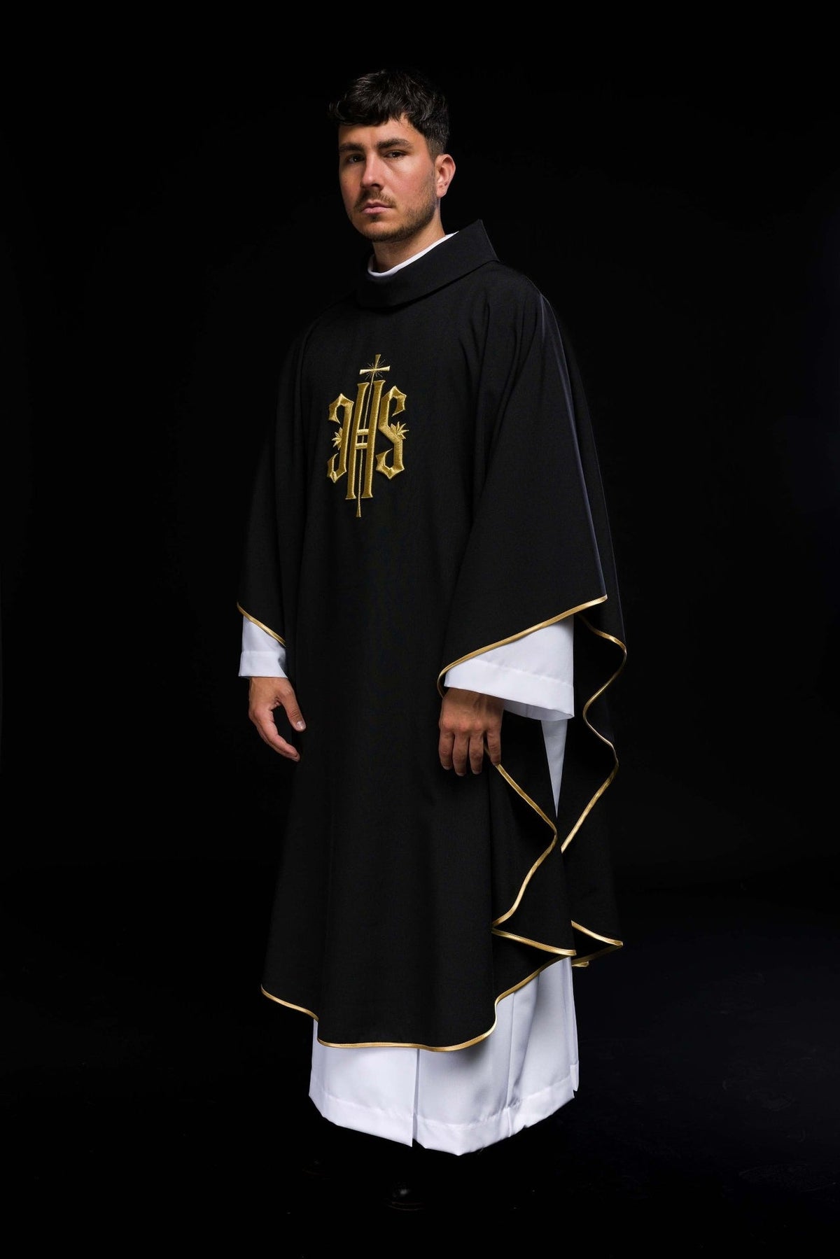 Black chasuble with gold IHS embroidery, three-quarter front view