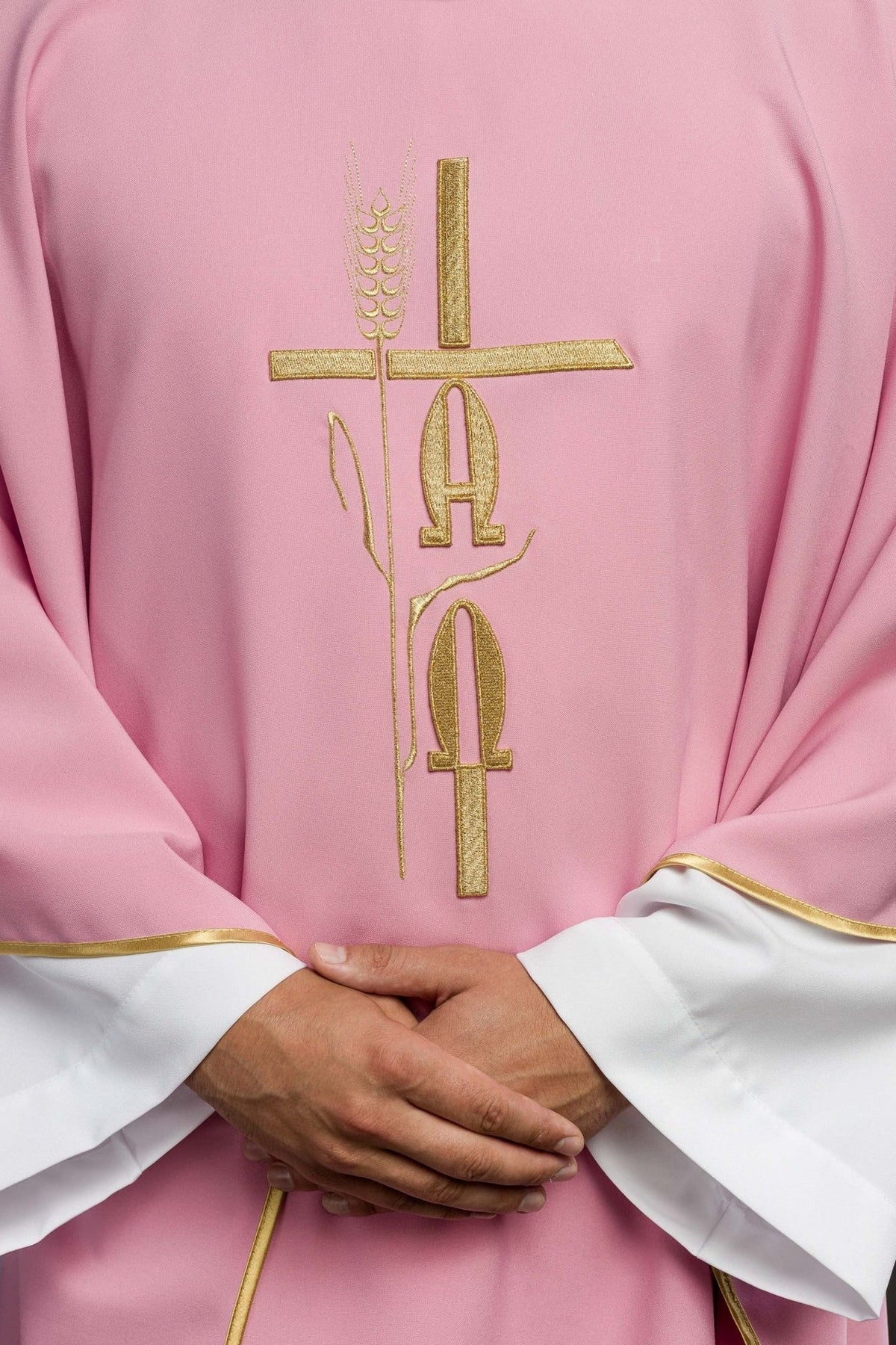 Chasuble close-up showing gold cross, IHS and rose embroidery on pink fabric