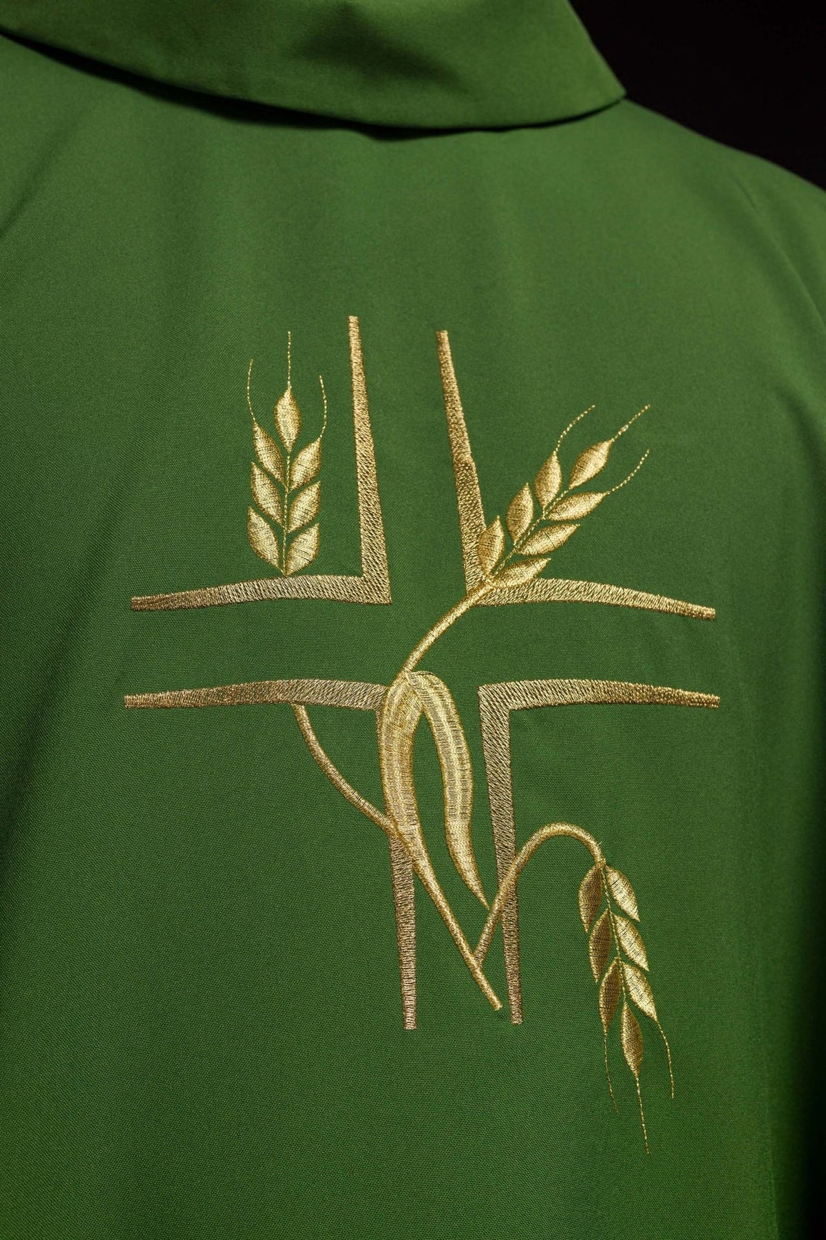Green chasuble close-up showing gold cross and wheat embroidery