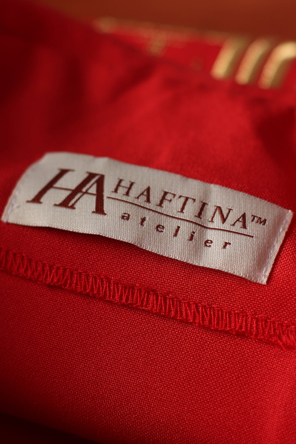 Red chasuble fabric close-up with gold trim and white sleeve