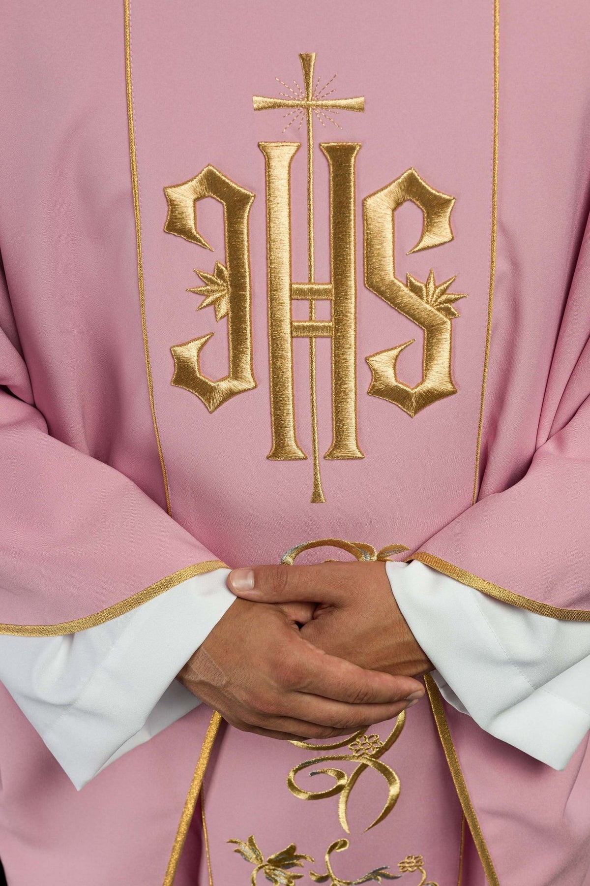 Rose chasuble close-up showing gold embroidered IHS and cross