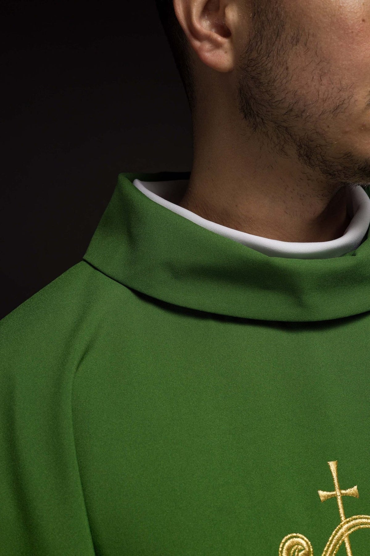 Green chasuble close-up showing gold IHS embroidery and trim