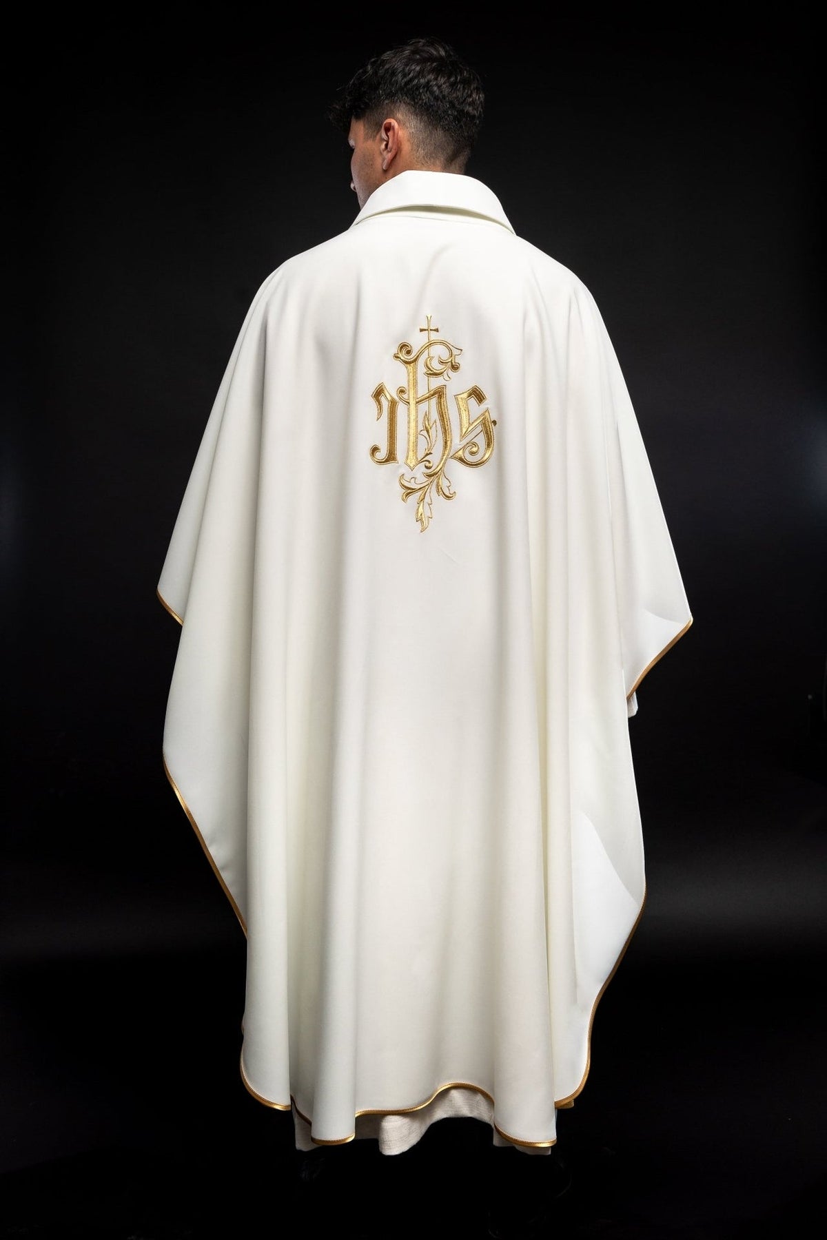 Cream chasuble back view showing centered gold IHS embroidery and scalloped trim