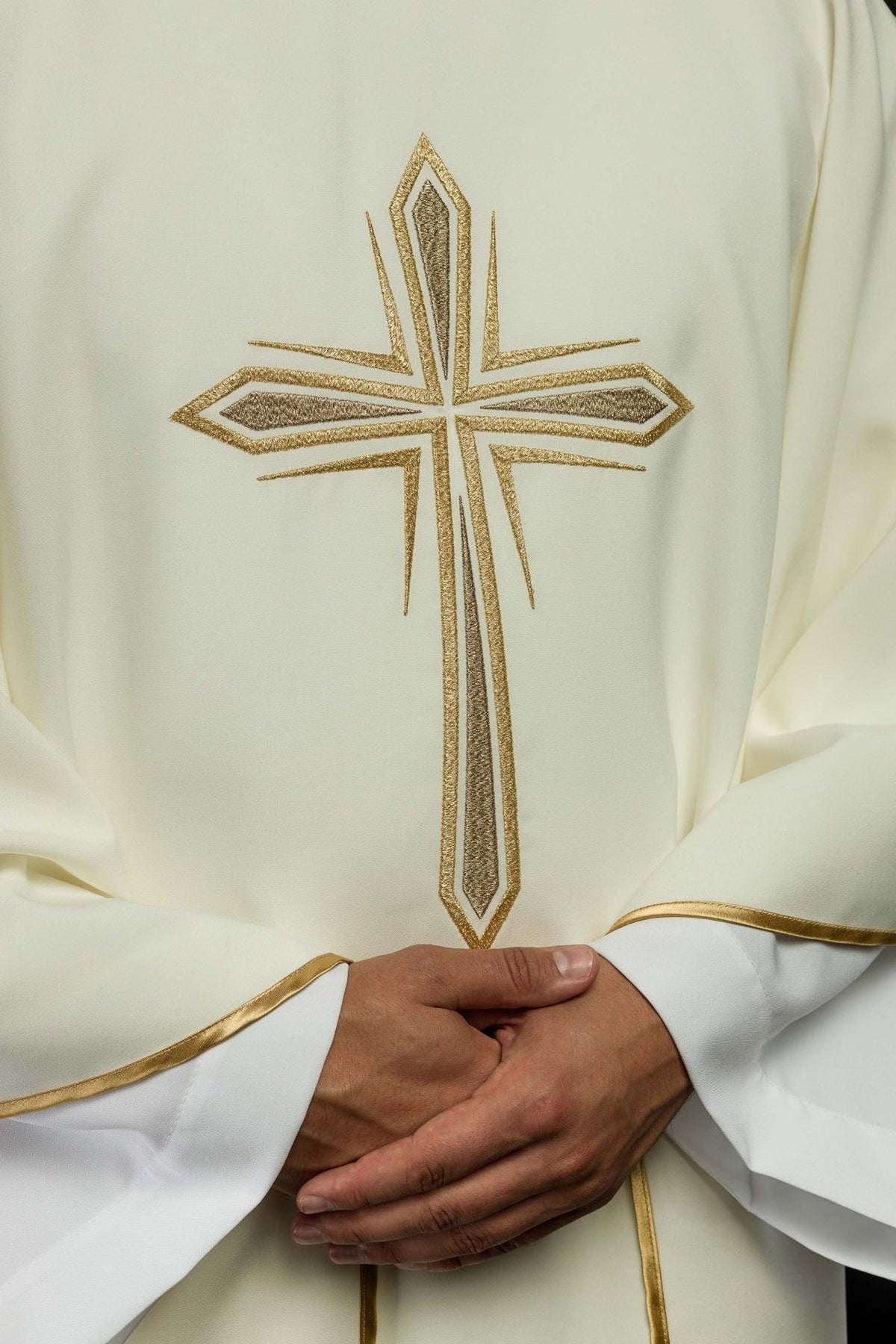 Chasuble close-up showing gold Holy Cross embroidery on ivory fabric