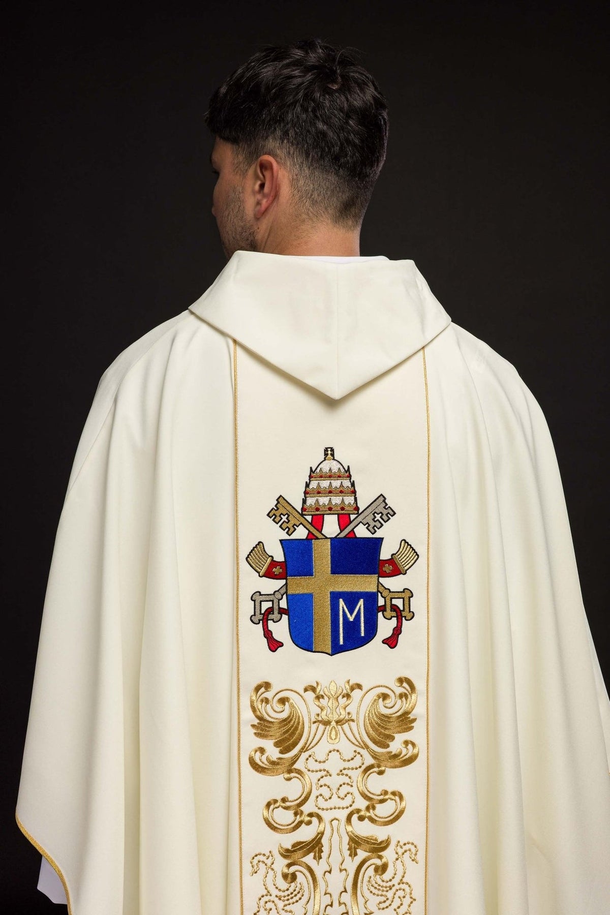 White chasuble worn from the back with papal coat of arms and gold embroidery