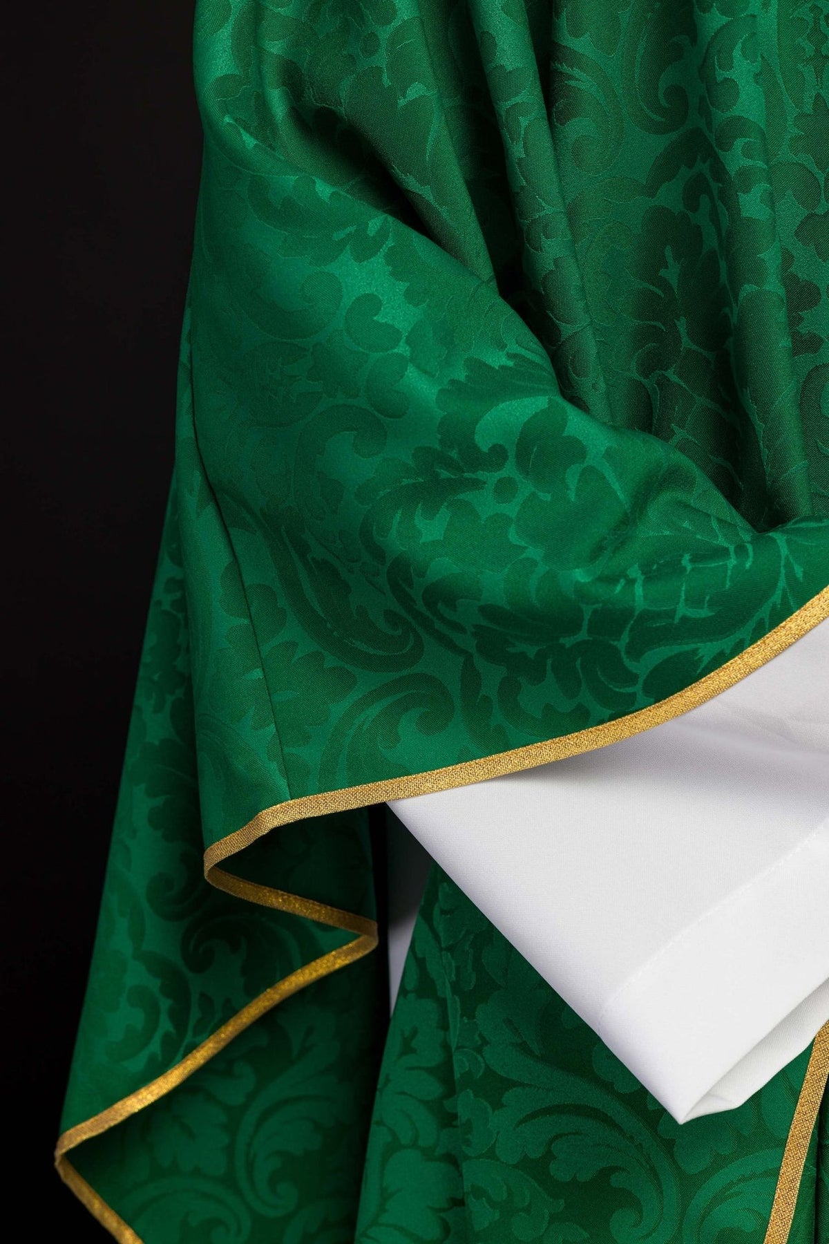 Green chasuble jacquard fabric close-up with gold trim at the edge