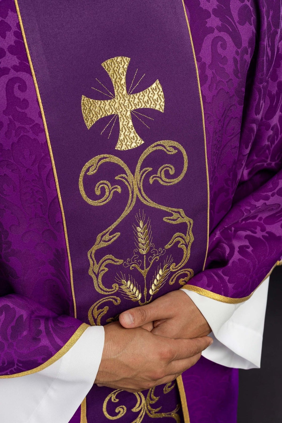 Purple chasuble close-up with gold cross and embroidered floral orphrey