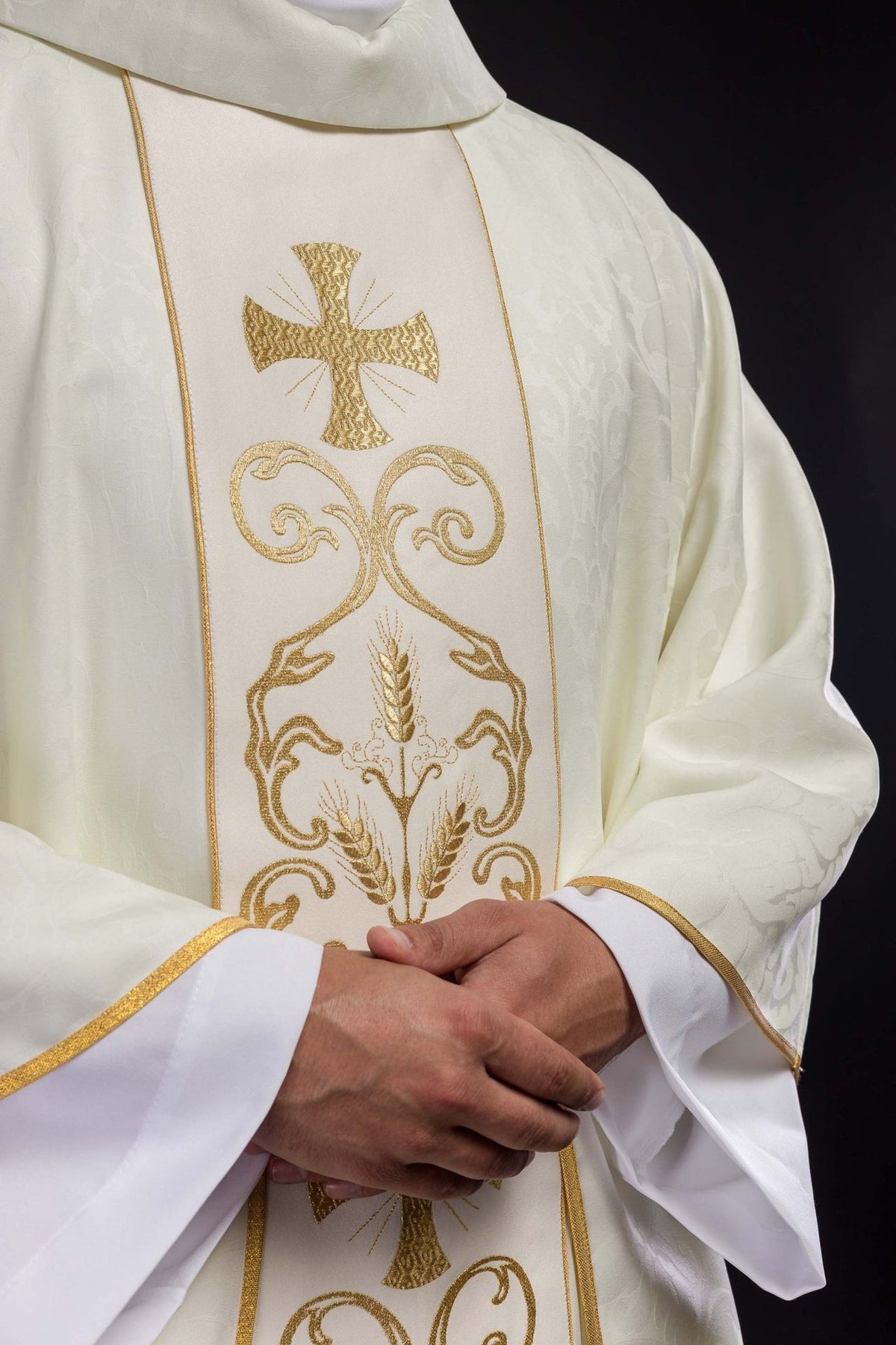 Liturgical chasuble close-up showing ivory orphrey with gold cross and floral embroidery