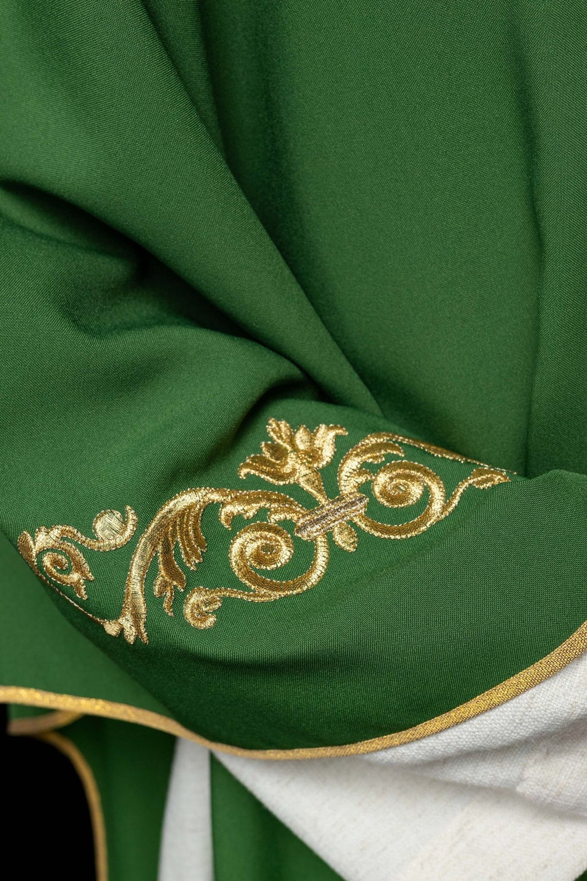 Green chasuble close-up showing gold embroidered sleeve trim