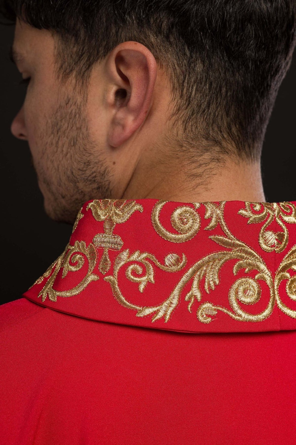 Red chasuble close-up showing gold decorative embroidery and satin trim