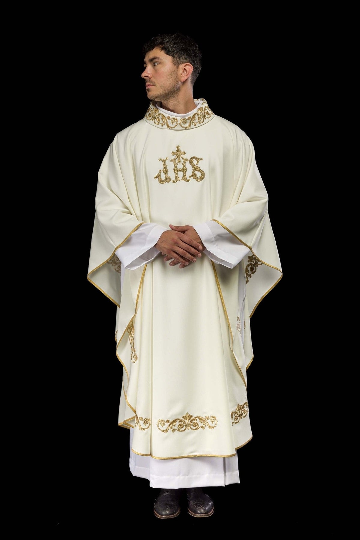 Ivory chasuble worn front view with gold embroidery, trim and IHS motif