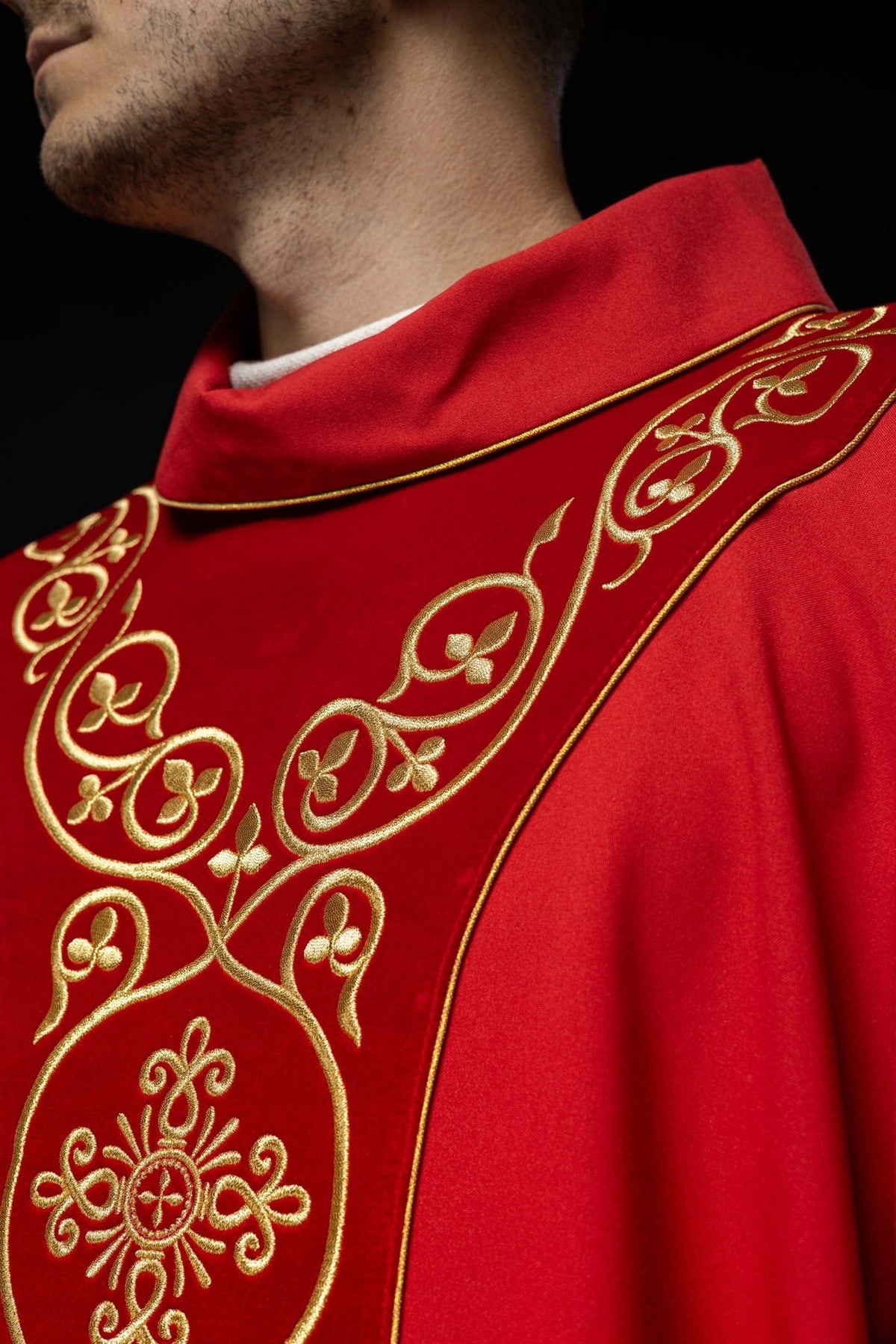 Red chasuble close-up showing stand-up collar and gold embroidered orphrey