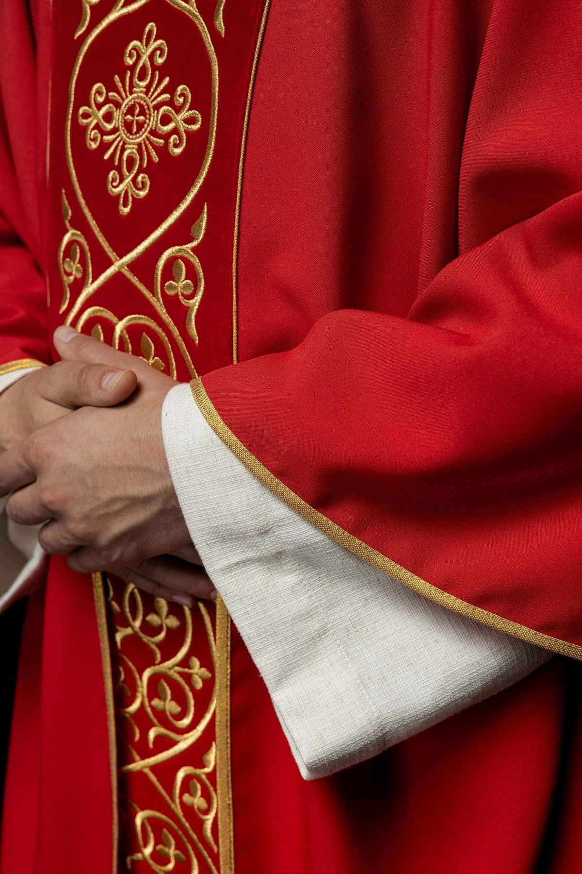 Red chasuble close-up showing gold embroidery on the velvet orphrey