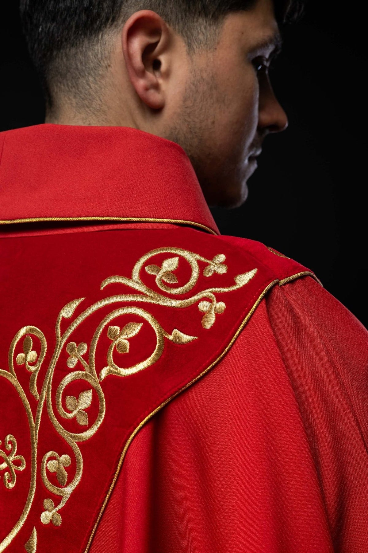 Red chasuble front detail showing repeated gold embroidery on the velvet orphrey