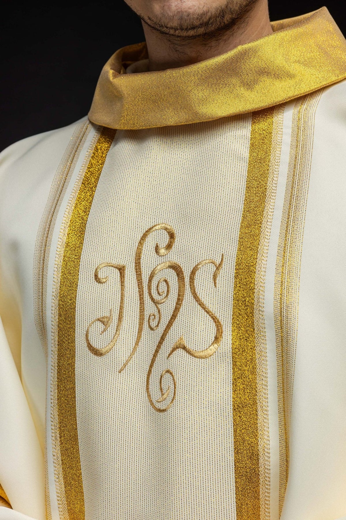 Chasuble close-up showing gold stand-up collar, vertical trim and IHS embroidery