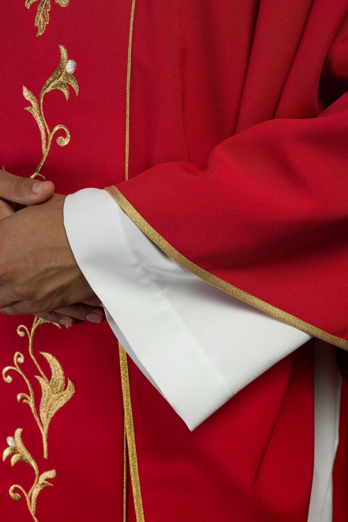 Red chasuble close-up showing gold trim along the sleeve edge